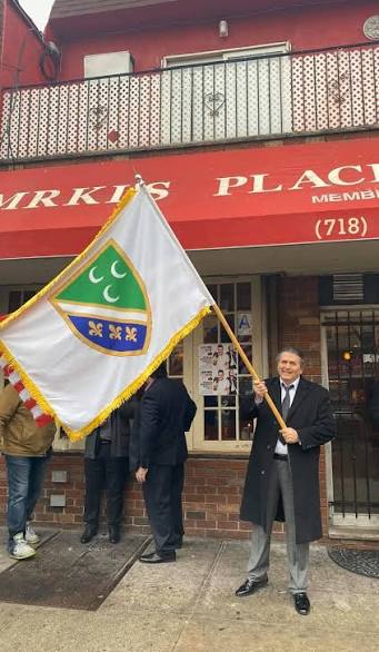 Mrki with a flag in front of his restaurant Mrki’s Place in Astoria